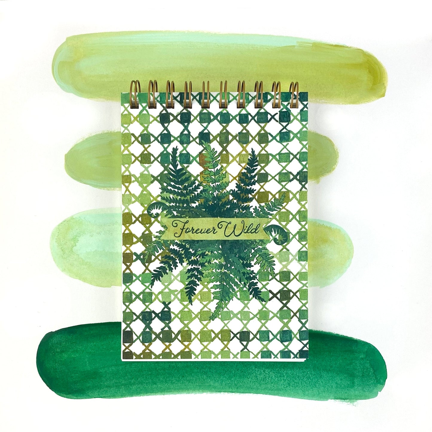Spiral Bound Notebook with hand painted green checkers and x's. In the center are wild green ferns and the worlds hand lettered "Forever Wild"