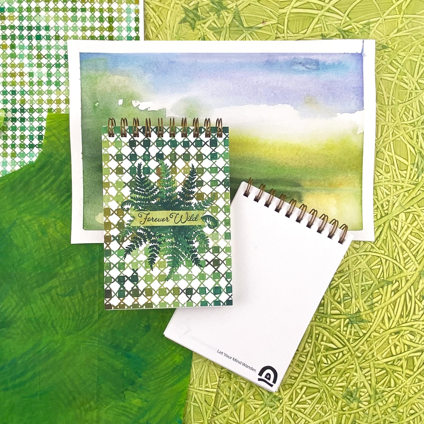 Spiral Bound Notebook with hand painted green checkers and x's. In the center are wild green ferns and the worlds hand lettered "Forever Wild"