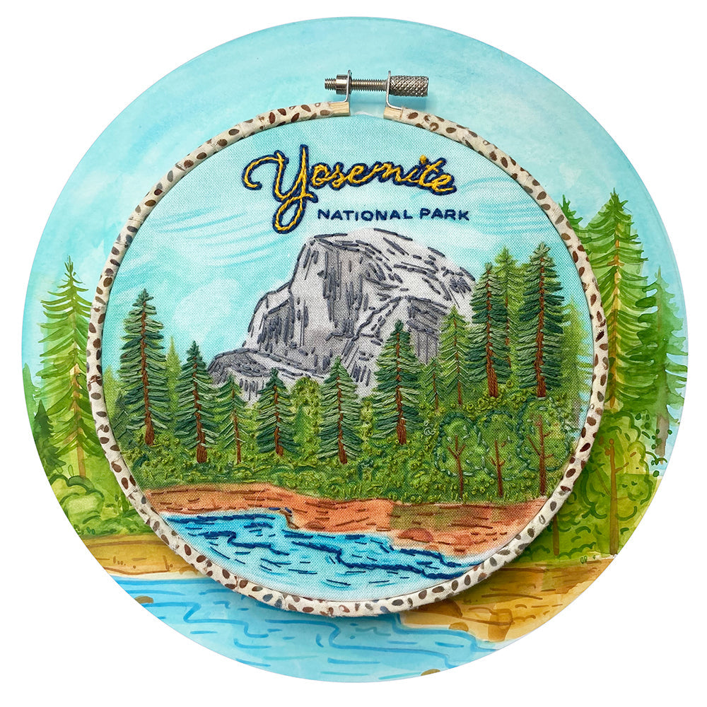 Yosemite National Park Embroidery kit in a hoop. Finished Embroidery sits on top of an illustration of Yosemite.