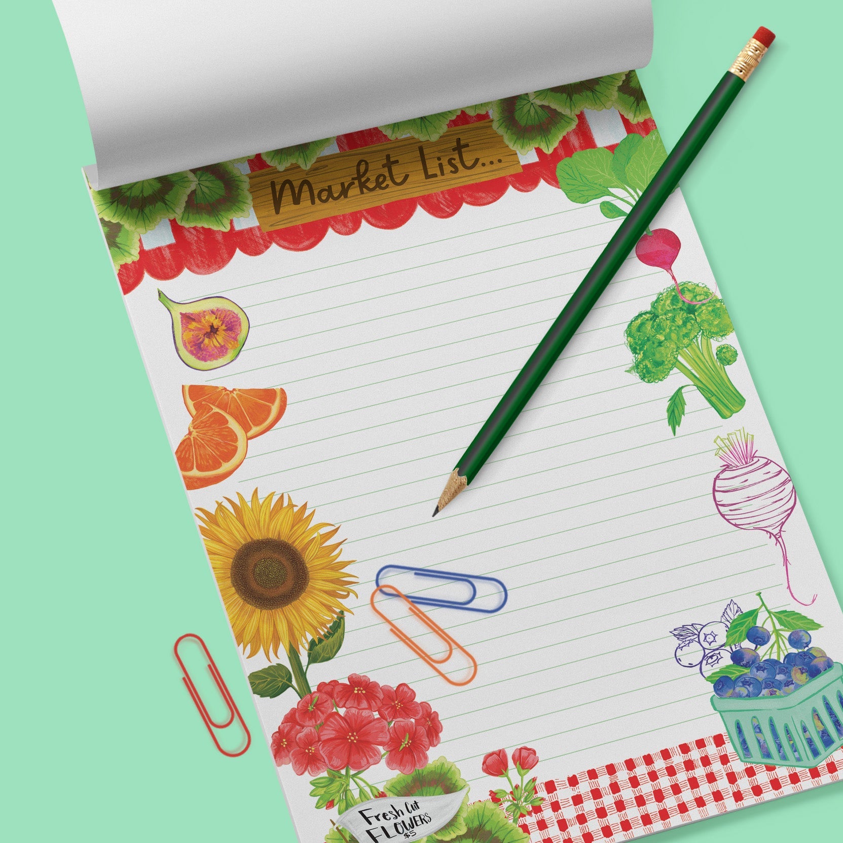 Mint green background with a Market List Notepad with colorful fruit and vegetable illustrations. Green pencil and 3 colorful paperclips. 