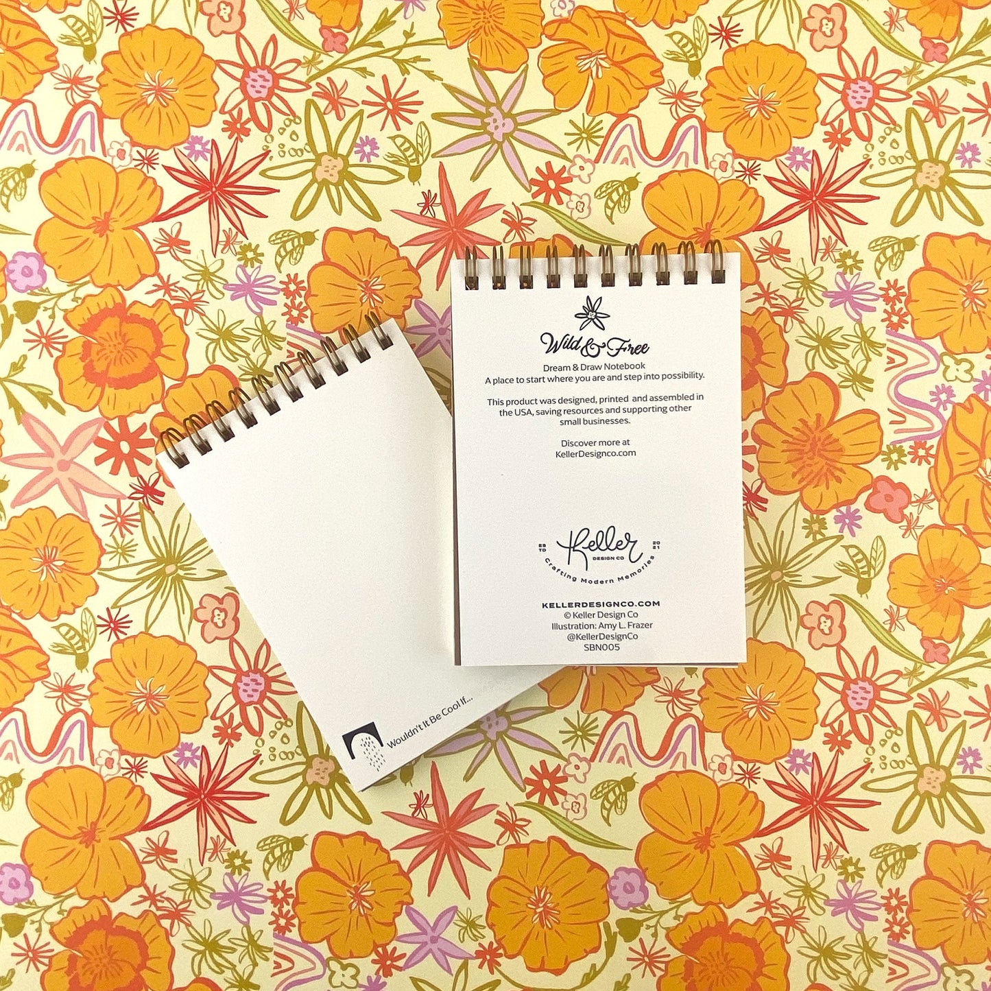 Spiral Bound Notebook with hand drawn colorful poppies and wildflowers in tones of orange , red, lavender and gold on a cream background. In the center is the handlettered phrase Wild and Free on a cream colored banner.